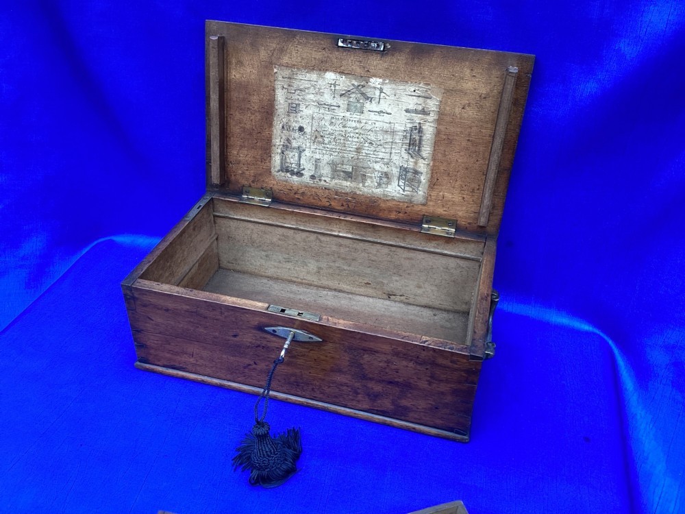 A rectangular Georgian mahogany tool box featuring a hinged lid with a central brass inlay plaque, a keyhole with a brass escutcheon, and visible dovetail joinery. View VI