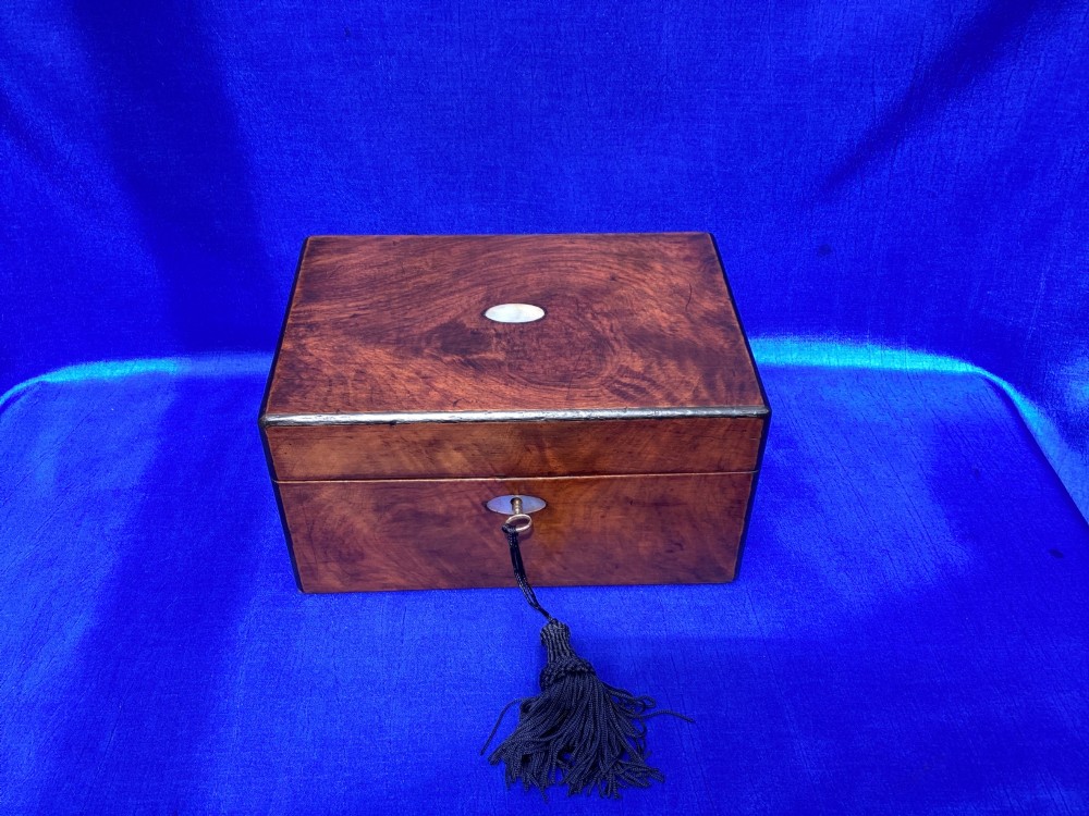 A rectangular Victorian mahogany box with a polished finish, a mother-of-pearl cartouche inlay on the lid, a keyhole escutcheon, and a brass key with a black tassel. View II
