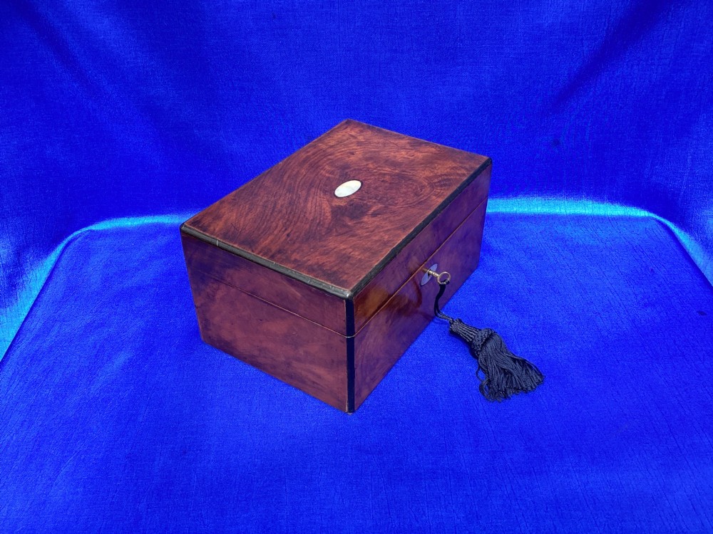 A rectangular Victorian mahogany box with a polished finish, a mother-of-pearl cartouche inlay on the lid, a keyhole escutcheon, and a brass key with a black tassel. View III