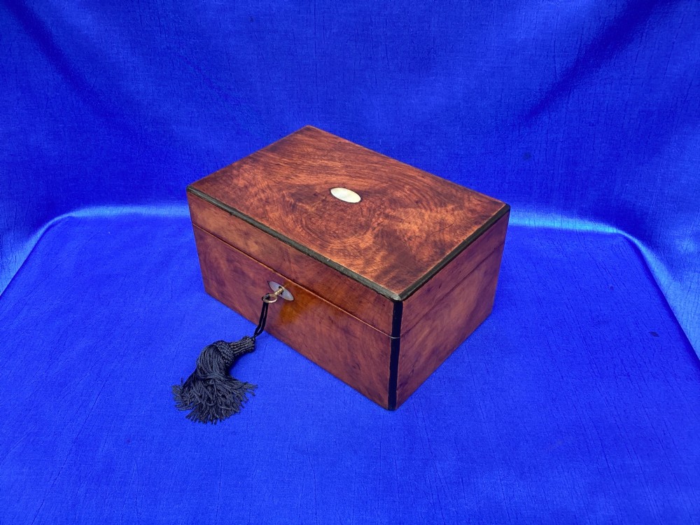 A rectangular Victorian mahogany box with a polished finish, a mother-of-pearl cartouche inlay on the lid, a keyhole escutcheon, and a brass key with a black tassel. View IV