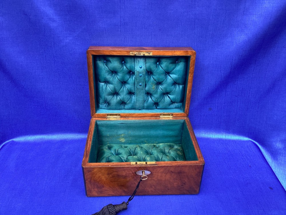 A rectangular Victorian mahogany box with a polished finish, a mother-of-pearl cartouche inlay on the lid, a keyhole escutcheon, and a brass key with a black tassel. View V