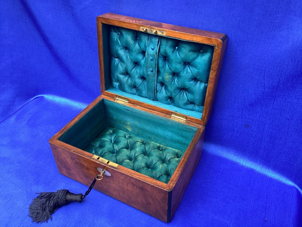 A rectangular Victorian mahogany box with a polished finish, a mother-of-pearl cartouche inlay on the lid, a keyhole escutcheon, and a brass key with a black tassel. View VI