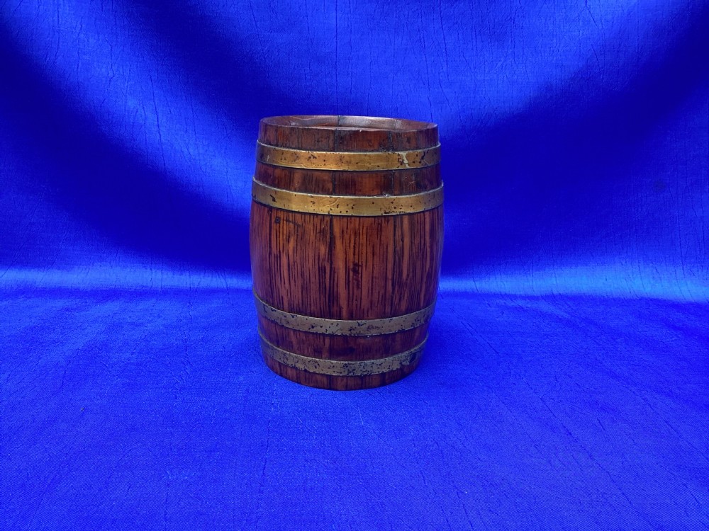 An Edwardian oak money box crafted in the form of a miniature coopered barrel with brass hoops.
