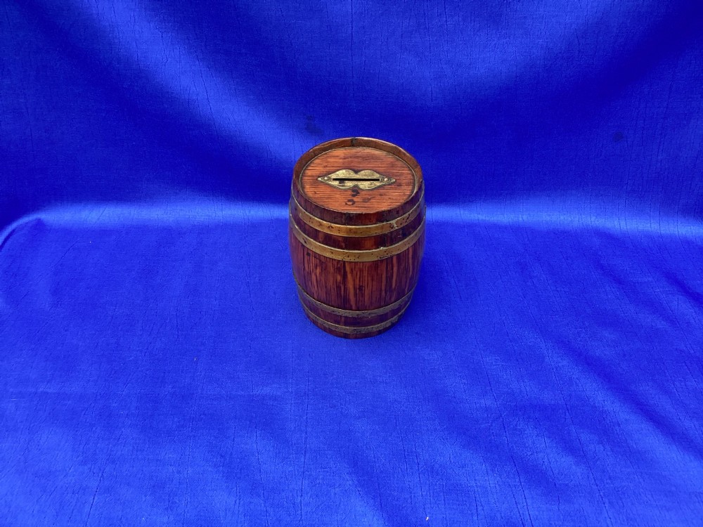 An Edwardian oak money box crafted in the form of a miniature coopered barrel with brass hoops. View II