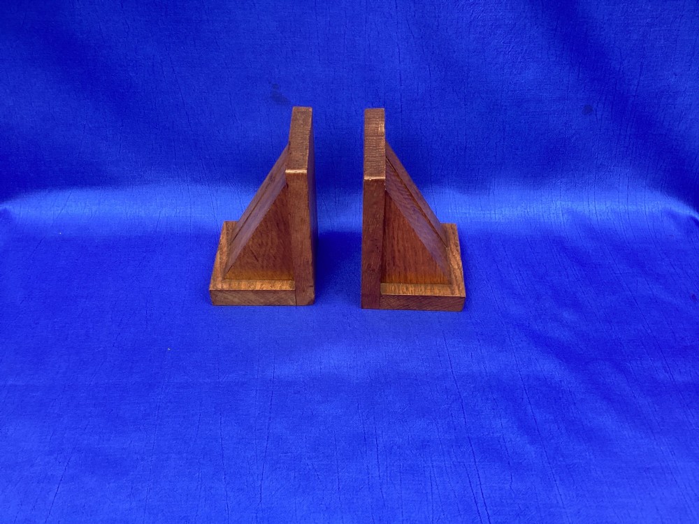 A pair of triangular solid oak wooden bookends featuring visible wood grain and a natural warm brown finish. View III