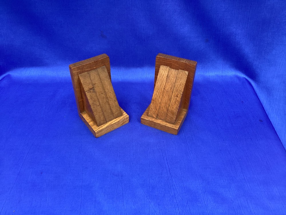 A pair of triangular solid oak wooden bookends featuring visible wood grain and a natural warm brown finish. View IV