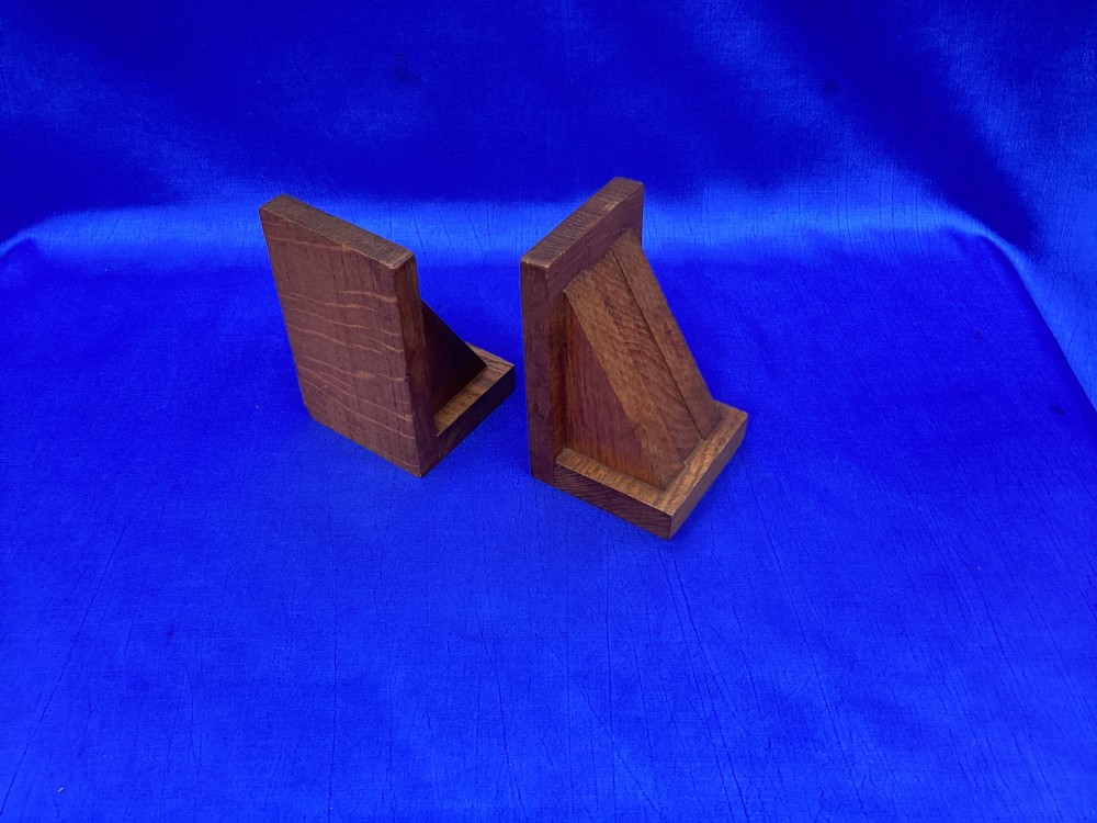 A pair of triangular solid oak wooden bookends featuring visible wood grain and a natural warm brown finish. View V