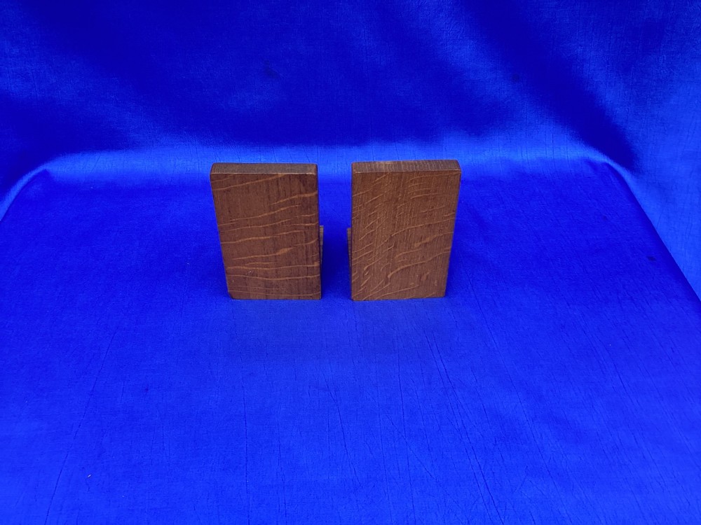 A pair of triangular solid oak wooden bookends featuring visible wood grain and a natural warm brown finish. View VI