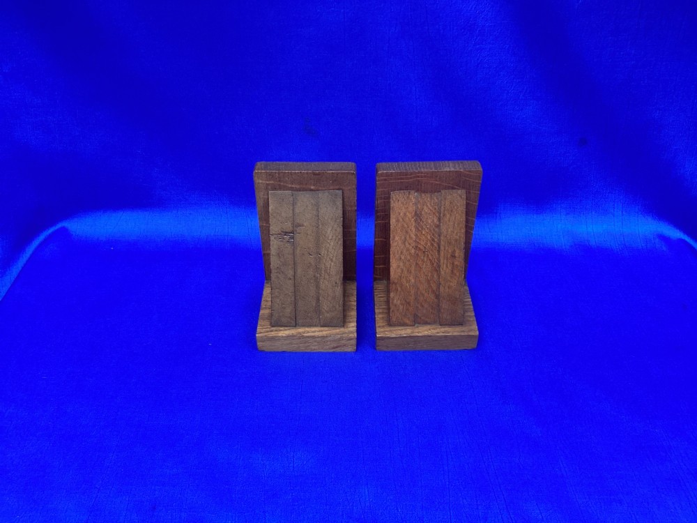 A pair of triangular solid oak wooden bookends featuring visible wood grain and a natural warm brown finish. View VII