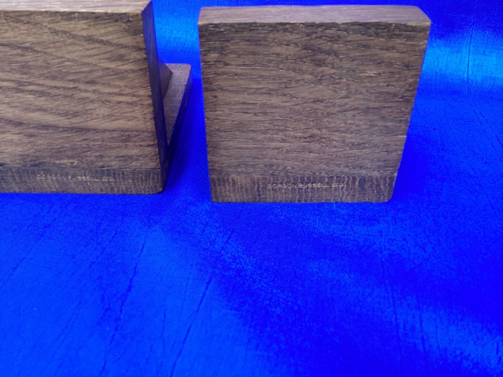 A pair of triangular solid oak wooden bookends featuring visible wood grain and a natural warm brown finish. View IX
