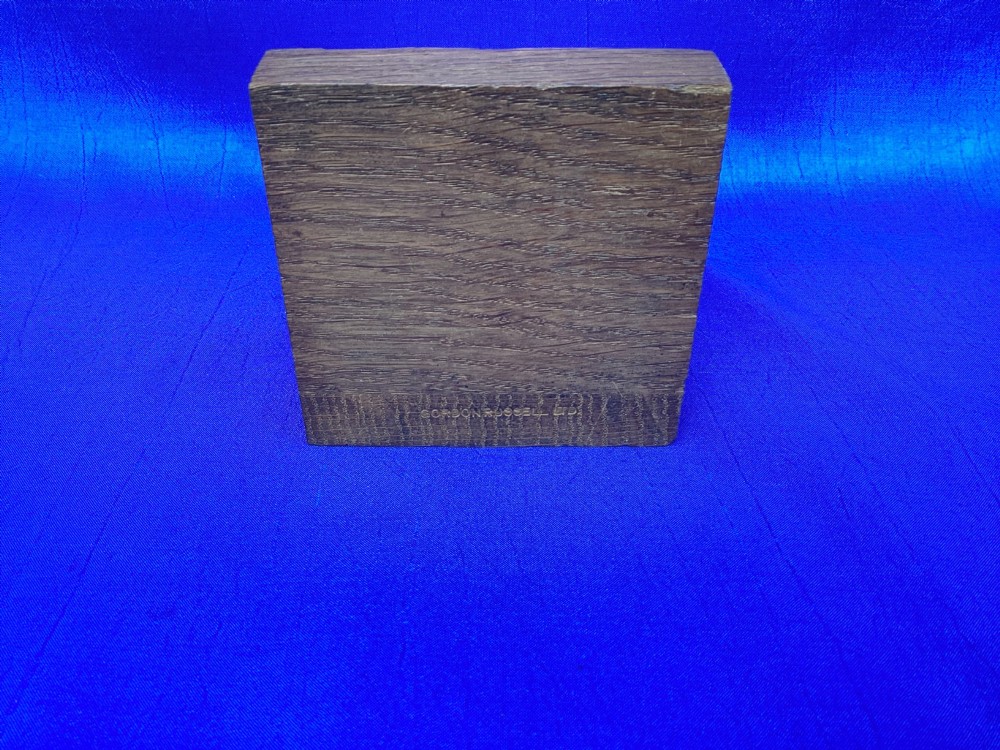 A pair of triangular solid oak wooden bookends featuring visible wood grain and a natural warm brown finish. View X