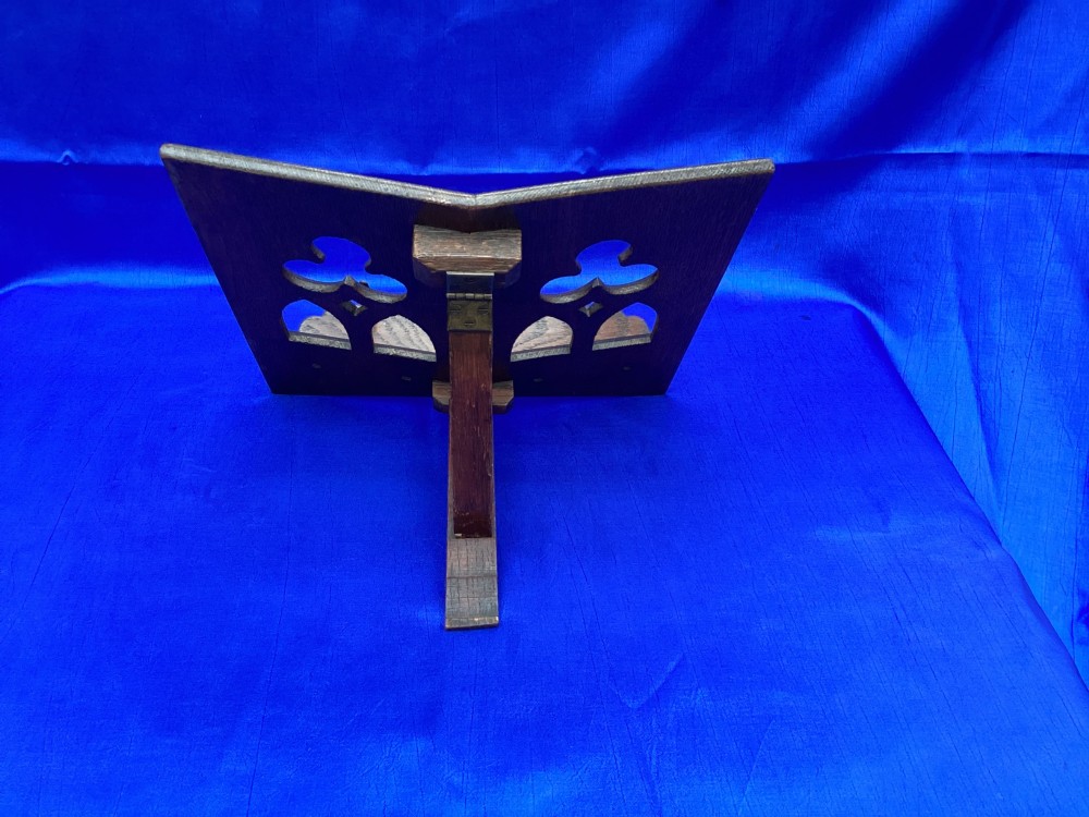 A dark carved oak desktop book stand featuring openwork Gothic lancet arches and trefoil tracery with brass page clips. View II