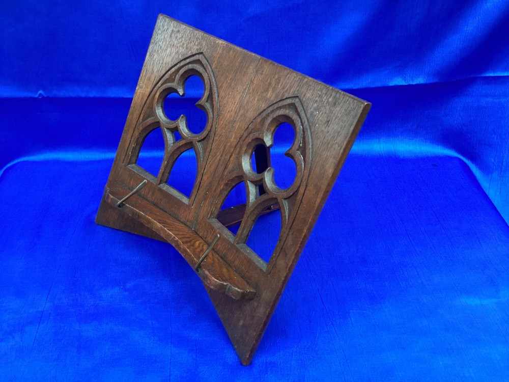 A dark carved oak desktop book stand featuring openwork Gothic lancet arches and trefoil tracery with brass page clips. View III