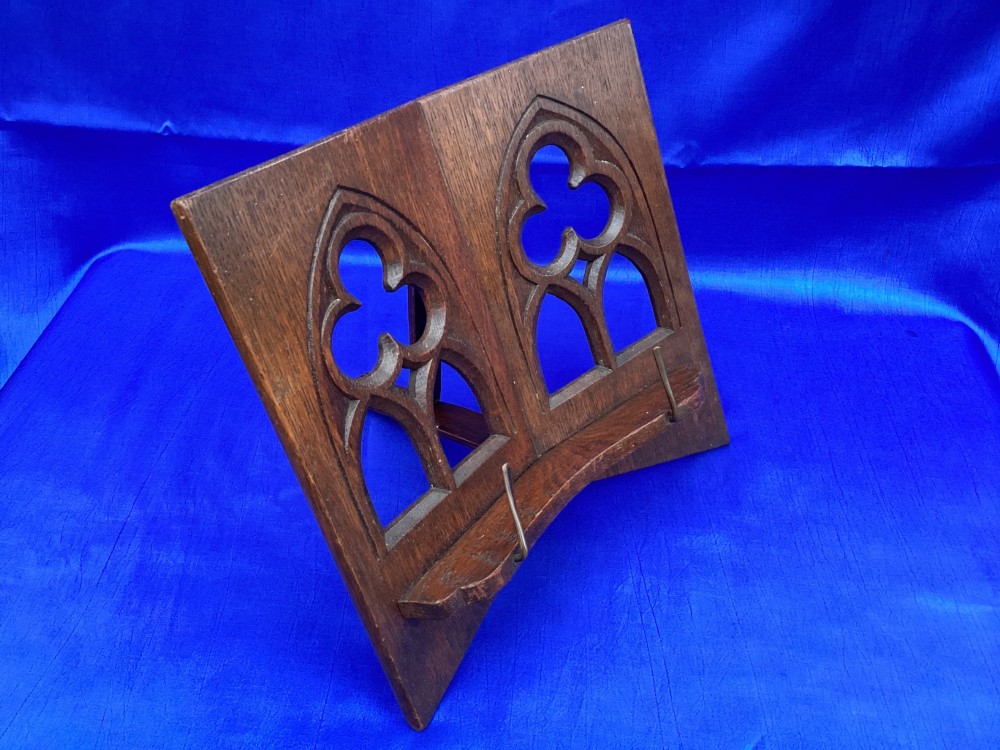 A dark carved oak desktop book stand featuring openwork Gothic lancet arches and trefoil tracery with brass page clips. View IV