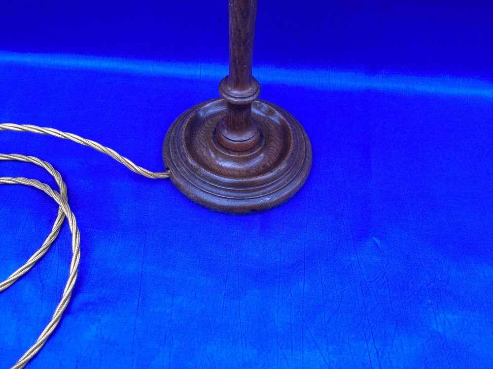 An antique turned oak table lamp featuring a bell-shaped variegated spatter glass shade and a yellow fabric-covered cable. View II