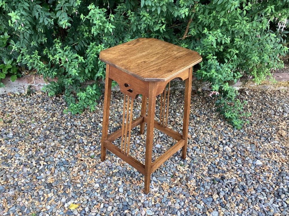 An Arts and Crafts solid oak plant table featuring an octagonal top, pierced cutout side aprons, central vertical slatted supports, and splayed legs with stretchers. View II