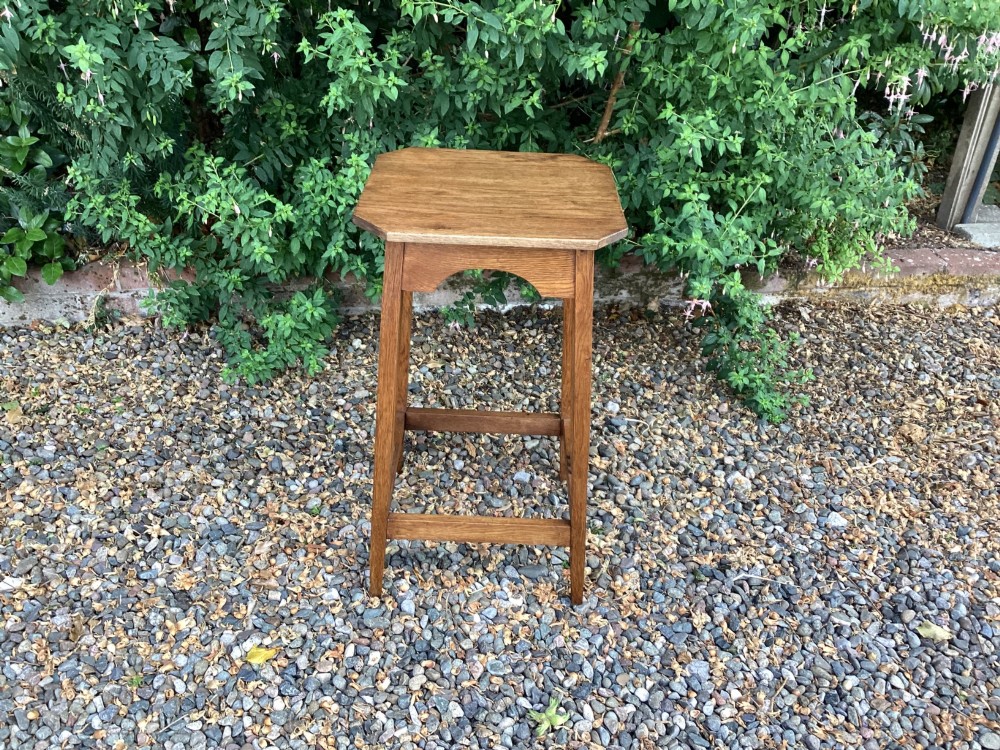 An Arts and Crafts solid oak plant table featuring an octagonal top, pierced cutout side aprons, central vertical slatted supports, and splayed legs with stretchers. View III