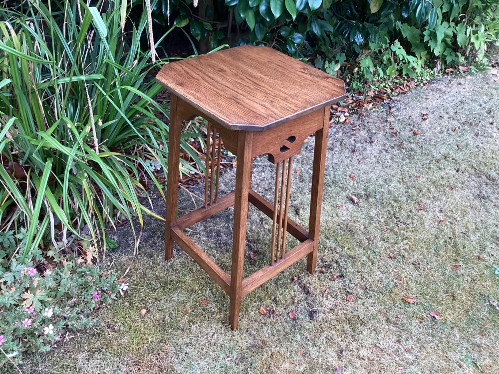 An Arts and Crafts solid oak plant table featuring an octagonal top, pierced cutout side aprons, central vertical slatted supports, and splayed legs with stretchers. View VIII