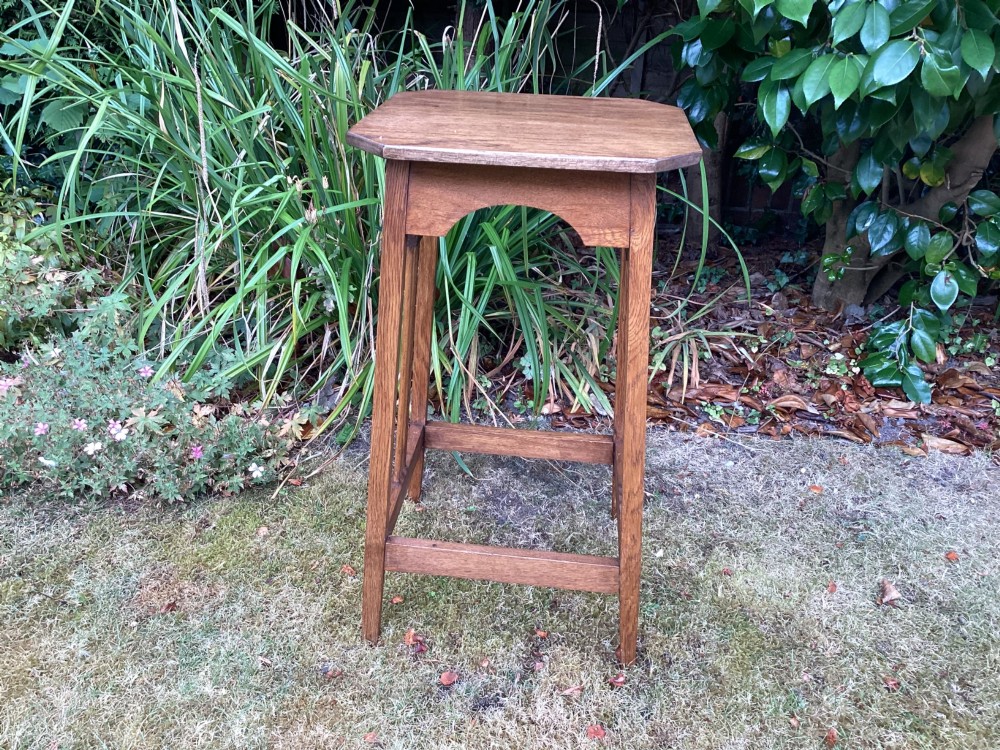 An Arts and Crafts solid oak plant table featuring an octagonal top, pierced cutout side aprons, central vertical slatted supports, and splayed legs with stretchers. View XII