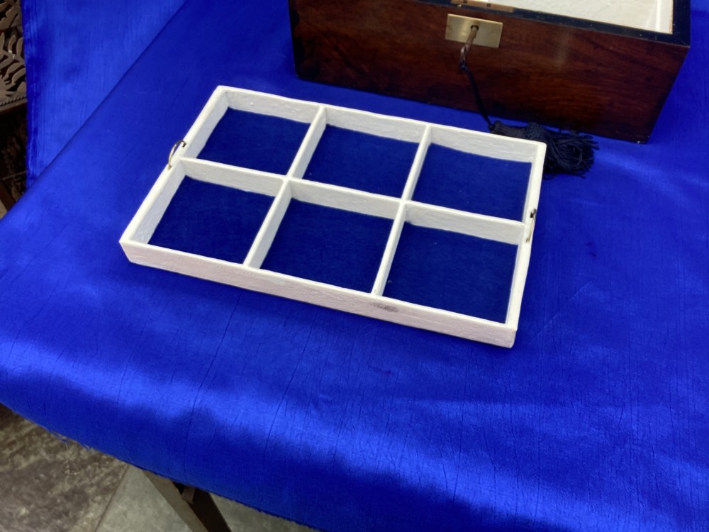 A rectangular Victorian mahogany box featuring decorative geometric inlay borders, a central crest motif on the lid, and a brass keyhole with a key and black tassel. View VI