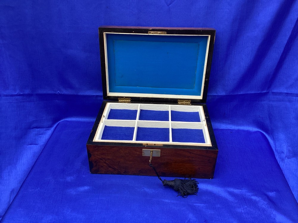 A rectangular Victorian mahogany box featuring decorative geometric inlay borders, a central crest motif on the lid, and a brass keyhole with a key and black tassel. View VII