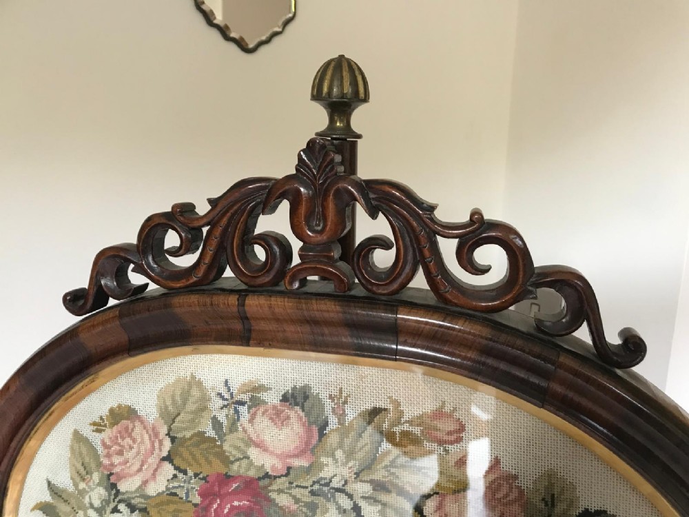 A Victorian rosewood pole screen featuring an oval floral needlework panel mounted on a turned column with a tripod base. View II