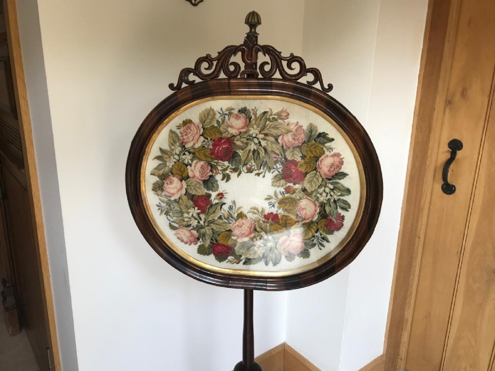 A Victorian rosewood pole screen featuring an oval floral needlework panel mounted on a turned column with a tripod base. View VI