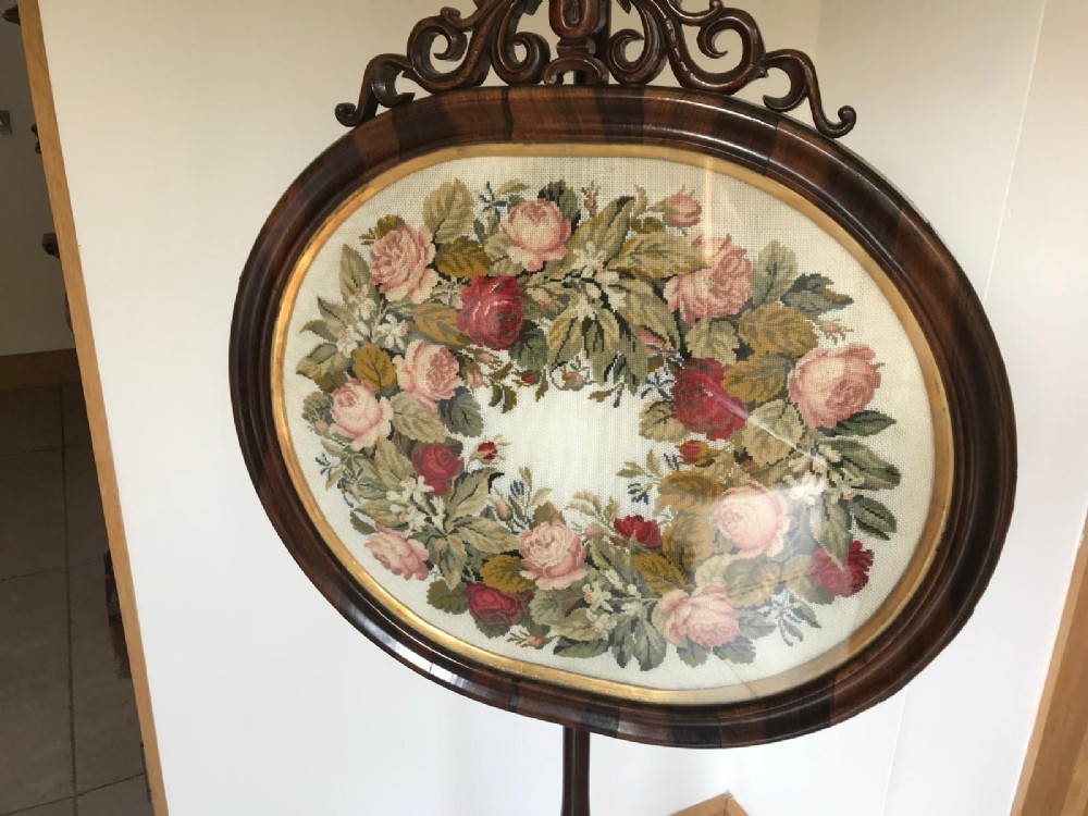 A Victorian rosewood pole screen featuring an oval floral needlework panel mounted on a turned column with a tripod base. View VII