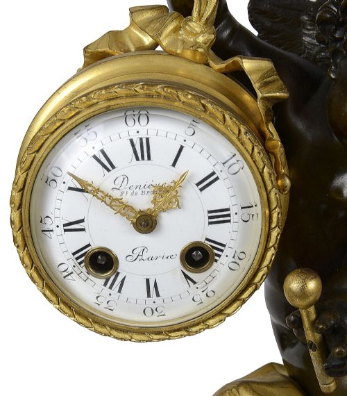 fig 2. A 19th-century French three-piece garniture set featuring a central patinated bronze cherub holding a clock atop a grey marble base, flanked by a pair of matching bronze cherub two-light candelabra.