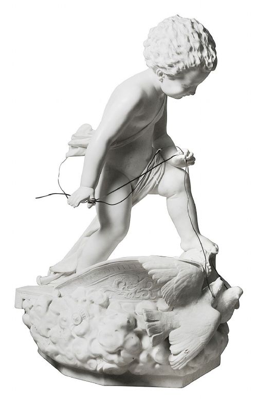fig 1. A 19th-century white carved marble sculpture depicting a child figure standing on a shell-shaped chariot pulled by a bird over clouds.