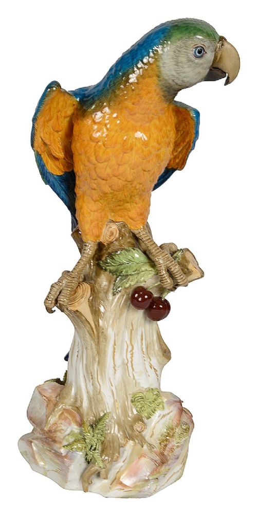 A polychrome porcelain figurine of a parrot with blue, green, and yellow feathers perched on a tree stump. View II