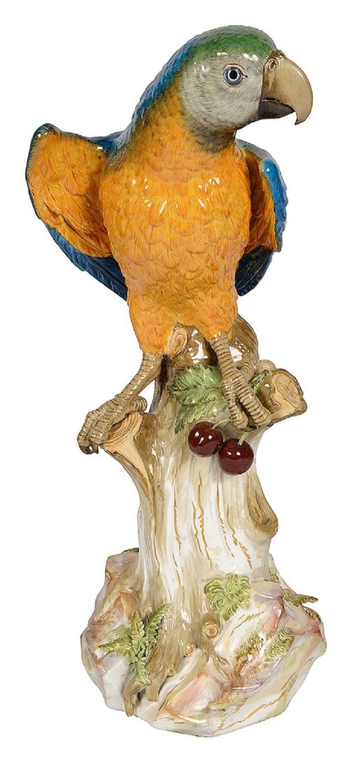 A polychrome porcelain figurine of a parrot with blue, green, and yellow feathers perched on a tree stump. View III