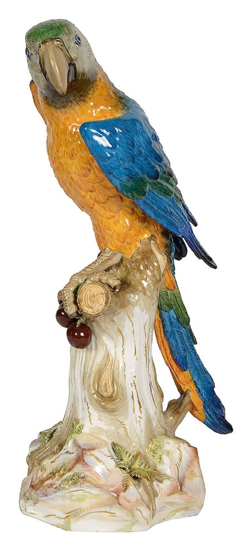 A polychrome porcelain figurine of a parrot with blue, green, and yellow feathers perched on a tree stump. View IV