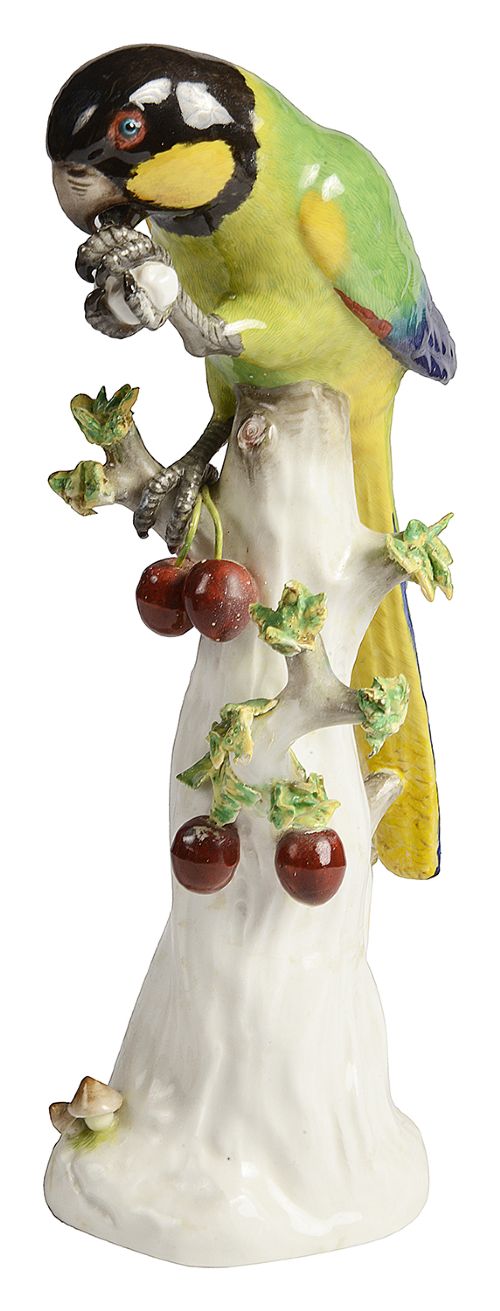 A 19th-century Meissen porcelain figurine featuring a colourful green, yellow, and black parrot perched atop a white tree trunk decorated with red cherries. View II