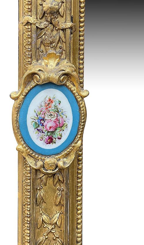 A large gilt-bronze wall mirror featuring an arched crest with sculpted putti, foliage mouldings, and oval Sevres porcelain plaques set along the frame. View VII