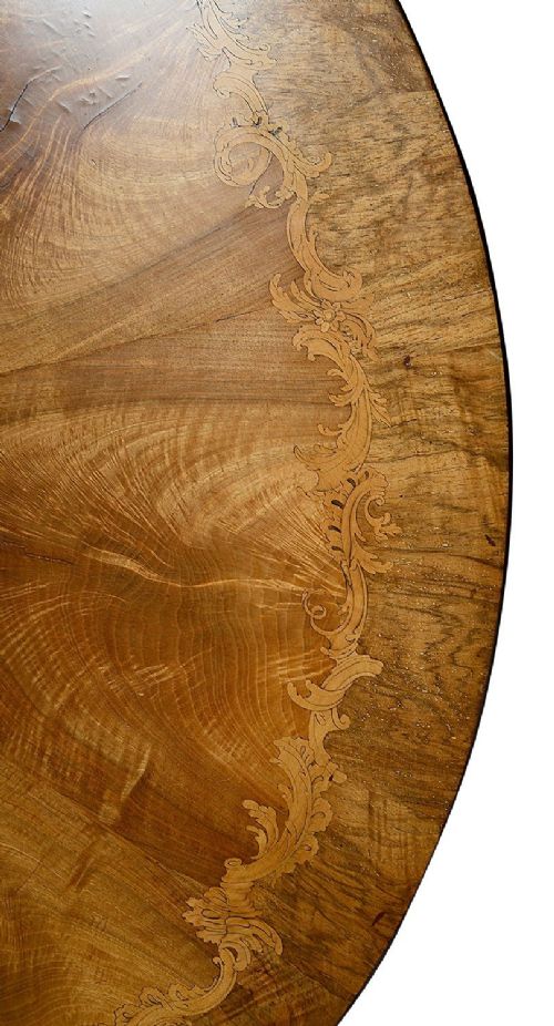 A circular Victorian walnut centre table featuring radial segment veneers, intricate floral marquetry, and a carved pedestal base with scroll feet. View V