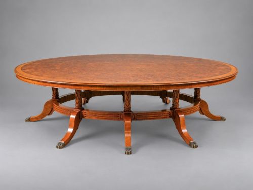 fig 2. A large oval burr walnut extending dining table featuring decorative satinwood crossbanding and pedestal legs fitted with brass castors.