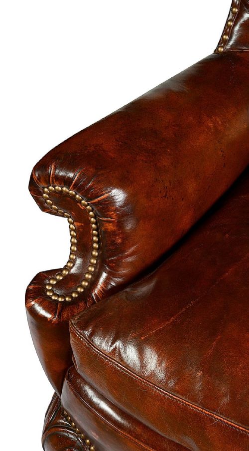 A pair of Georgian style chestnut brown leather wingback armchairs featuring deep button tufting, brass stud trimming, and carved cabriole legs. View VI