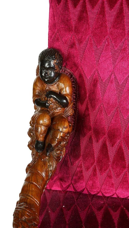 An ornate Venetian style armchair with high back red diamond velvet upholstery and detailed carved wooden human figures forming the armrests and legs. View VI