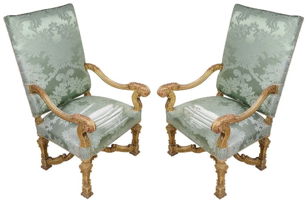 A pair of 19th-century William and Mary style armchairs with gold giltwood carved frames and high backrests upholstered in sage green damask fabric.