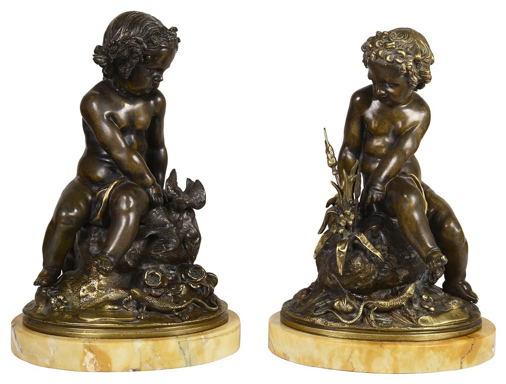 A pair of 19th-century patinated bronze sculptures depicting cherubic putti seated on rocky outcrops, mounted on circular yellow marble plinths.