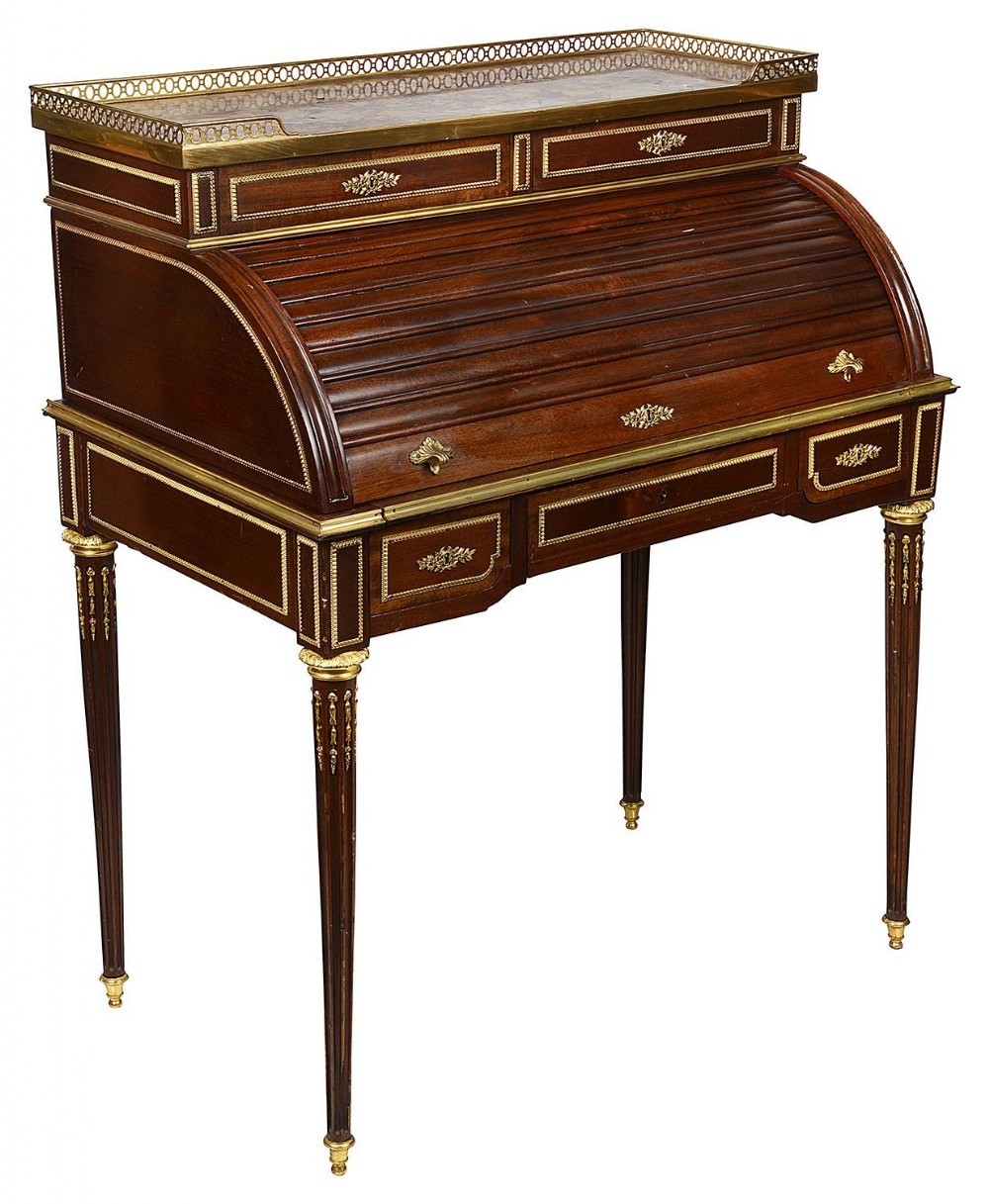 A 19th-century Louis XVI style dark mahogany roll-top bureau featuring gilt-bronze mounts, fluted tapered legs, and a pierced brass gallery top.