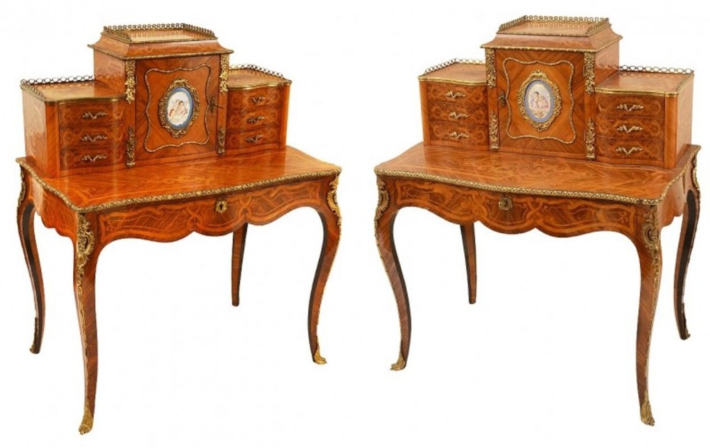A pair of 19th-century French bonheur du jour writing desks featuring inlaid marquetry wood, gilt-bronze mounts, central painted porcelain plaques, and cabriole legs.