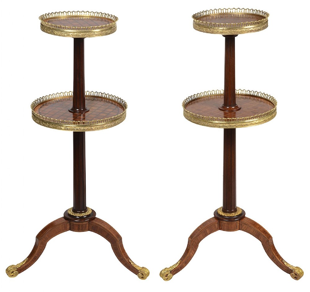 A pair of Victorian two-tier etageres featuring parquetry inlaid circular tops, pierced brass galleries, fluted central columns, and tripod bases with gilt mounts.