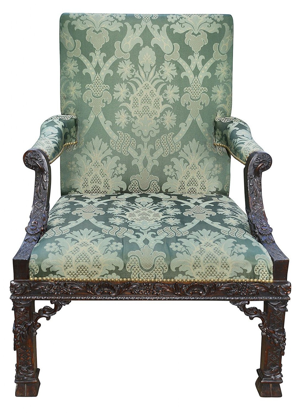 A Chippendale style Gainsborough armchair featuring carved mahogany legs and arm supports, upholstered in green patterned damask fabric with brass stud trimming.