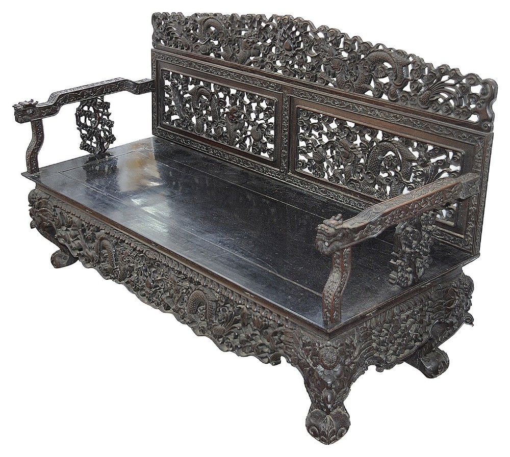 A 19th-century Chinese dark hardwood sofa featuring elaborate relief carvings of dragons across the back panels, armrests, and lower apron.