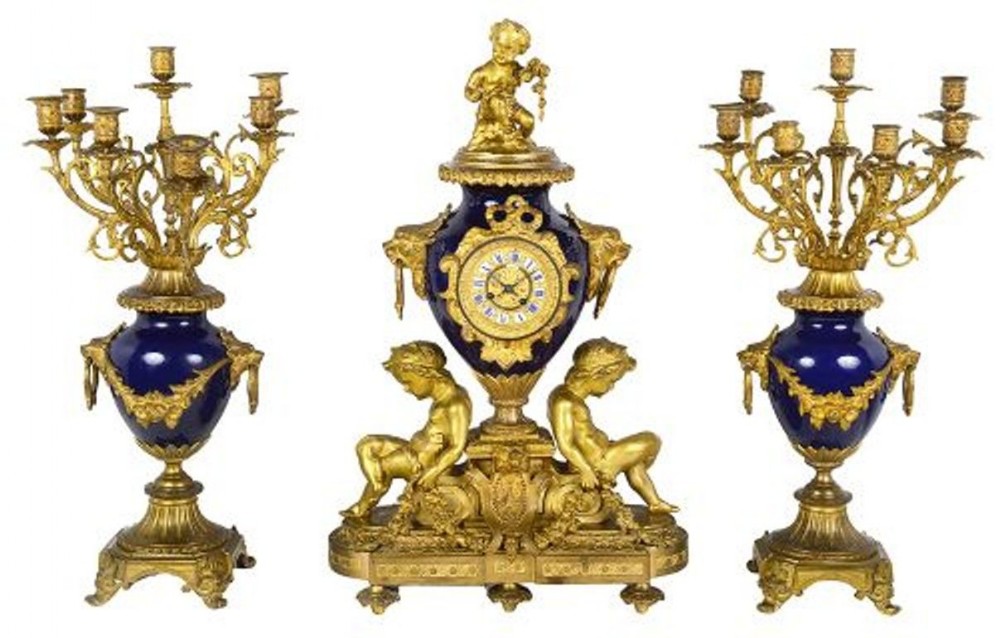 A 19th-century French garniture set with a central cobalt blue porcelain clock topped by a bronze cherub, flanked by two multi-branch gilt candelabra.