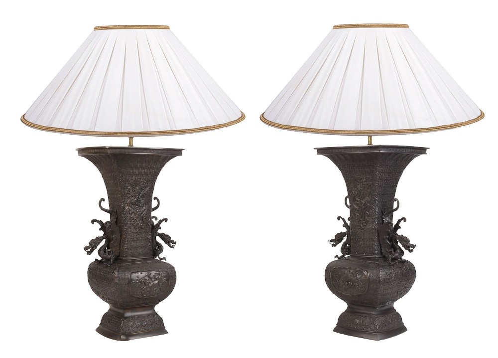 A pair of dark patinated Japanese Meiji period bronze vases converted into table lamps, complete with pleated off-white shades.