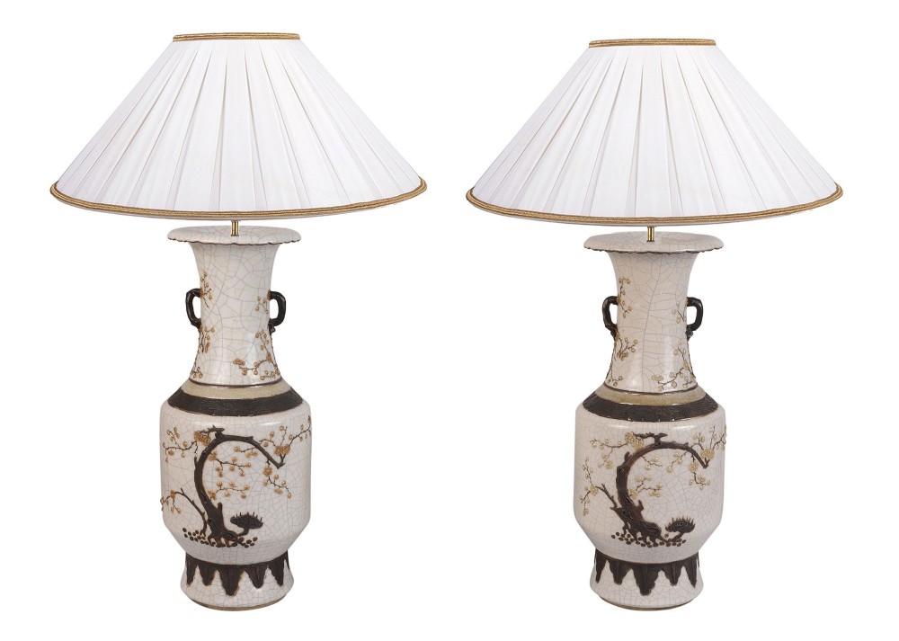 A pair of 19th-century Chinese crackleware ceramic vase table lamps featuring relief prunus blossom decoration and pleated cream shades.