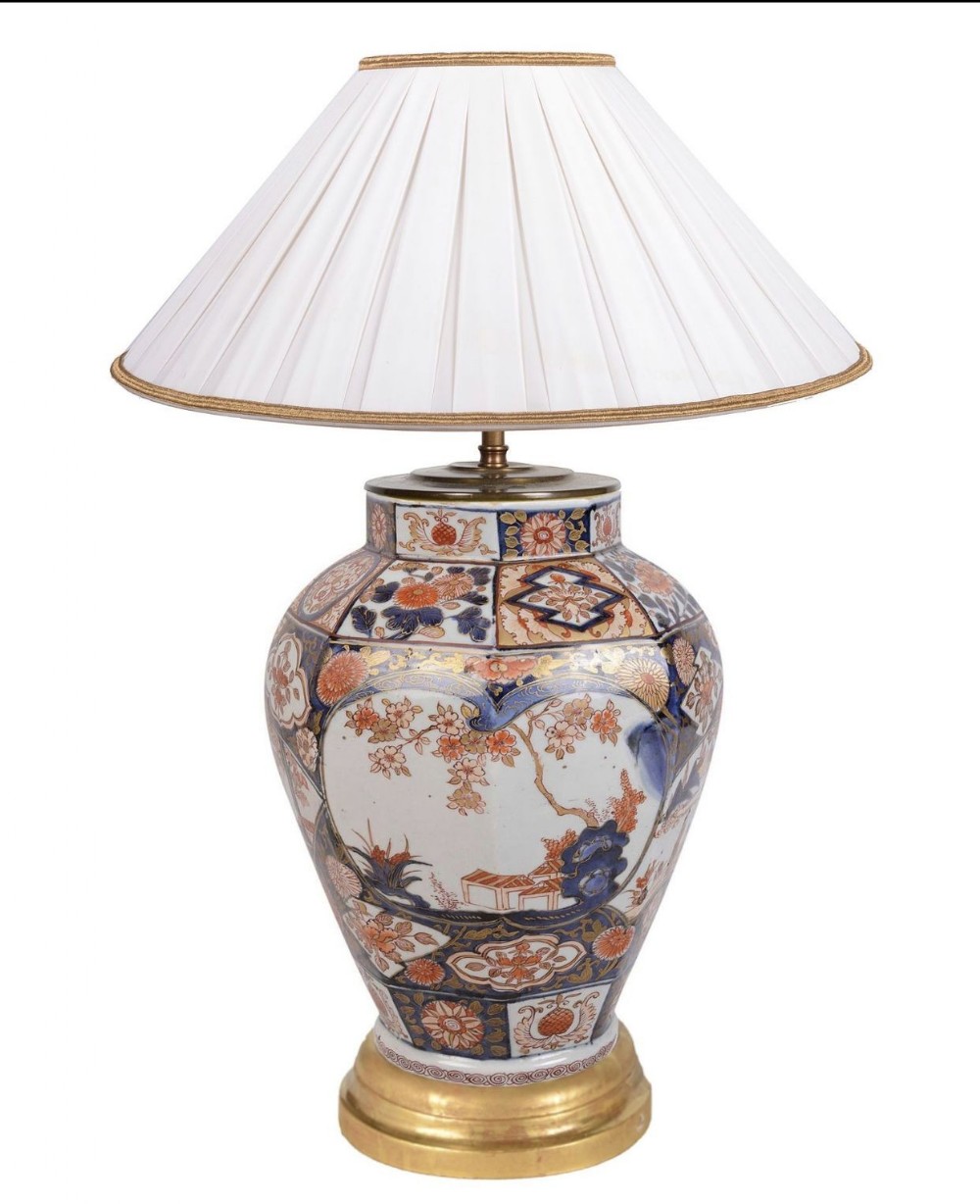 An 18th-century Japanese Imari porcelain vase converted into a table lamp with a pleated off-white fabric shade.